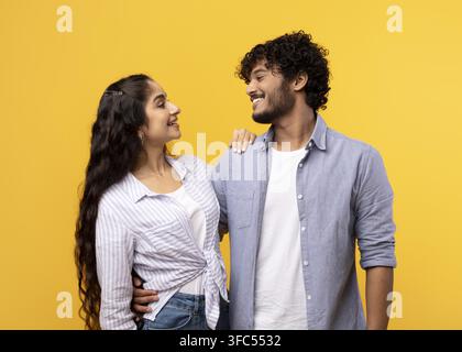 Coppia che sorride e si abbraccia su sfondo giallo, concetto di relazione felice Foto Stock