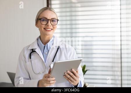 Ritratto di una dottoressa terapista donna in camice bianco che tiene un tablet digitale Foto Stock