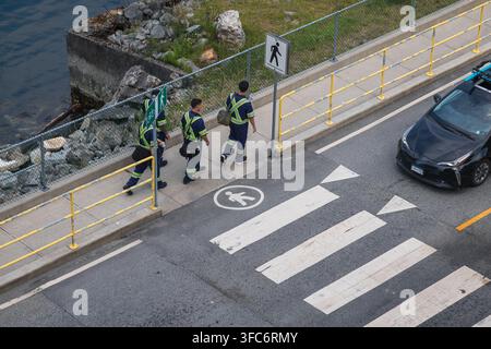Veicolo di condivisione di auto Evo a un passaggio pedonale con operai che camminano lungo il marciapiede del lungomare a Vancouver, British Columbia. Foto Stock