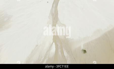 Vista aerea che scopre le vaste dune di sabbia bianca e il letto del fiume sinuoso di Lencois Maranhenses, creando un paesaggio arido astratto Foto Stock