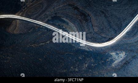 Vista aerea di una strada tortuosa che attraversa i campi di lava vulcanica scura del cratere Tjarnargigur a Skaftarhreppur, Islanda. Foto Stock