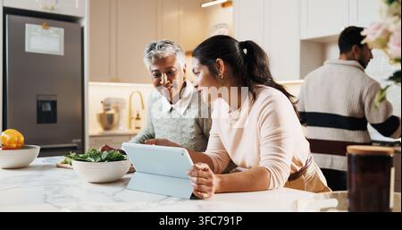 Cucina, tablet e donna con madre anziana a casa per preparare un pasto insieme nel fine settimana. Cucina, tecnologia digitale e figlia adulta con Foto Stock