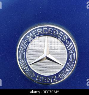 Emblema della marca automobilistica Mercedes Benz con stella a tre punte su una superficie blu del veicolo Foto Stock