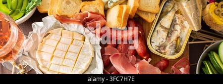 Un colorato banco di salumi offre un'invitante selezione di formaggi, affettati, pane fresco, noci e hummus cremoso, perfetto per la condivisione in un casu Foto Stock