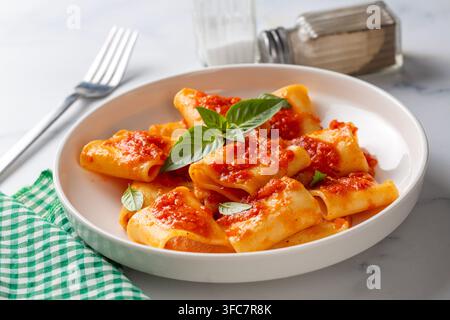 Pasta Paccheri italiana tradizionale con salsa di pomodoro e basilico fresco su sfondo rustico Foto Stock
