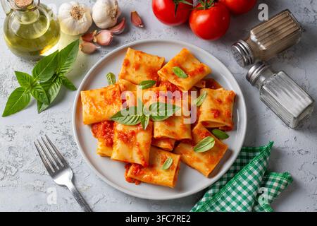 Pasta Paccheri italiana tradizionale con salsa di pomodoro e basilico fresco su sfondo rustico Foto Stock