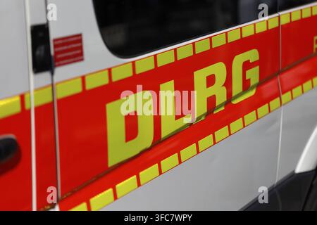 Primo piano di un furgone bianco con marcature DLRG rosse e gialle e strisce riflettenti. Messa a fuoco sulla portiera del passeggero Foto Stock