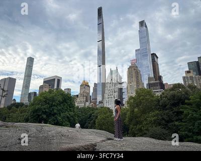 Un visitatore si trova sulle rocce, in controluce contro lo skyline di Midtown. New York, New York, Stati Uniti, 5 agosto 2026. Foto Stock