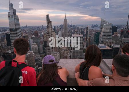 I visitatori si appoggiano al parapetto del ponte di osservazione, di fronte all'Empire State Building. New York, New York, Stati Uniti, 17 agosto 2026. Foto Stock
