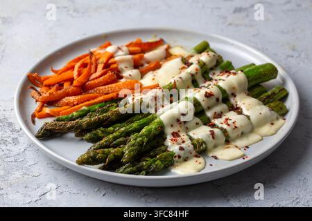 Asparagi e carote arrostiti con salsa bianca cremosa e fiocchi di peperoncino Foto Stock