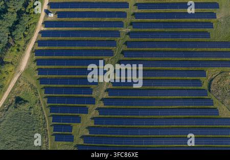 Vista aerea di una grande fattoria solare con file di pannelli fotovoltaici installati su un campo erboso a Uckermark, Brandeburgo, Germania. Foto Stock