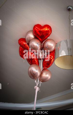 Palloncini rossi a forma di cuore e palloncini rosa metallici con testo scritto a mano per la celebrazione del 15° compleanno Foto Stock