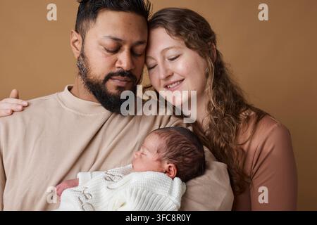 Ritratto familiare interrazziale di genitori che tengono un neonato addormentato mostrando amore, legame e genitorialità Foto Stock