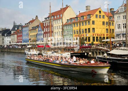 Canale Nyhavn a Copenaghena, Danimarca, con edifici storici colorati e un battello turistico che passa in una giornata di sole. Foto Stock