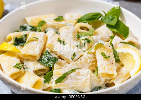 Pasta rigatoni fatta in casa con ricotta al limone saporita, basilico e spinaci Foto Stock