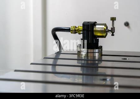 Strumento di lavorazione industriale di precisione montato su un tavolo macchina, primo piano di attrezzature per la lavorazione dei metalli con collegamento idraulico Foto Stock
