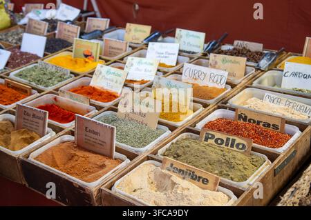 Varieta' colorata di spezie macinate, erbe tradizionali e fiocchi di peperoncino in scatole di legno con etichette scritte a mano, che offrono una ricca selezione culinaria per Foto Stock