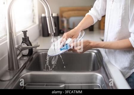 Donna che osserva le stoviglie in cucina. Foto Stock