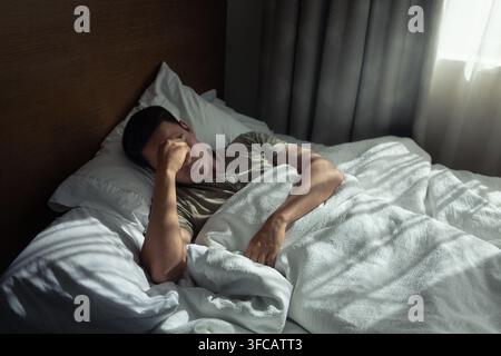Uomo che si sveglia dopo una notte agitata. Foto Stock