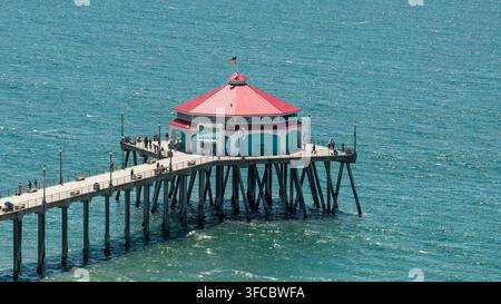 Vista aerea del molo di Huntington Beach con il suo iconico edificio dal tetto rosso che si estende nel turchese Oceano Pacifico a Huntington Beach, California Foto Stock