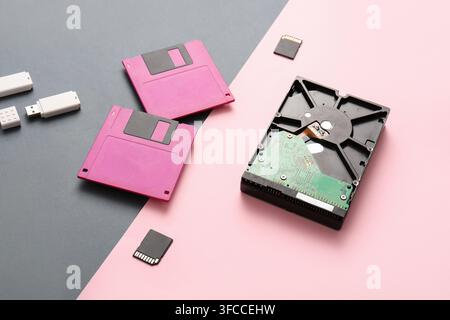 Evoluzione dello storage dei dati e progresso tecnologico: floppy disk, hard drive, chiavetta USB e scheda SD su sfondo diviso Foto Stock