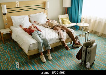 Uomo e donna sdraiati sul letto nella camera d'albergo dopo un lungo viaggio Foto Stock