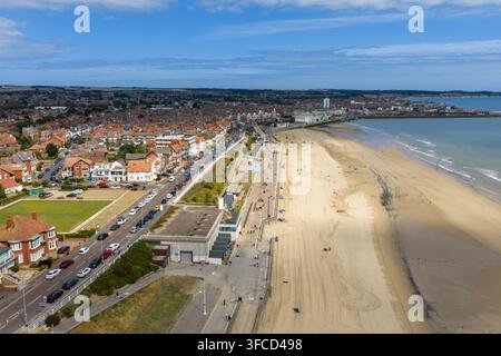 Foto aerea lungo il lungomare di Bridlington con passeggiata sabbiosa, strada costiera, case, capanne da spiaggia, edifici urbani e riva del Mare del Nord formi Foto Stock