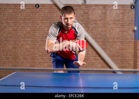 Atleta maschio che tiene una pagaia e una palla prima di servire Foto Stock
