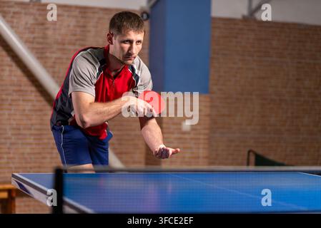Atleta maschio che tiene una pagaia e una palla prima di servire Foto Stock