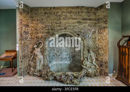 Un muro ceramico su larga scala con due figure Art Nouveau incornicia una nicchia fontana a forma di conchiglia nel Musée de l'École de Nancy a Nancy, Grand Est, Francia. Motivi di canne e un rilievo floreale coprono le piastrelle smaltate tutt’intorno. Foto Stock