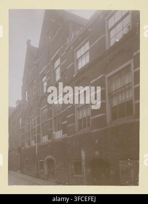 Parte della facciata di Nieuwstraat 10 a Dordrecht, fotografia, annotazione: ''Berkelpoort' parte della facciata di Nieuwstraat 10, Gen. 1911, Dordrecht', Nieuwstraat (Dordrecht), 1911, fotografo, Dordrecht, Attribuito a, carta, cartone, stampa argentica al collodio alla luce del giorno, altezza 219 mm x larghezza 162 mm, edilizia urbana., Una facciata di edificio in mattoni alta e stretta riempie l'inquadratura, mostrando una serie di finestre allineate verticalmente con telai e vetri in legno, alcune con tende trasparenti e altre che riflettono la luce; bande decorative in pietra corrono orizzontalmente attraverso la muratura tra le file di finestre, e ad arco Foto Stock