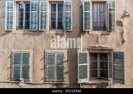 Persiane blu incorniciano diverse finestre sulla facciata di una casa segnata dal tempo in Rue de Guise nel centro storico di Nancy, Grand Est, Francia. Una delle finestre è socchiusa, con una tenda visibile dietro di essa. Foto Stock