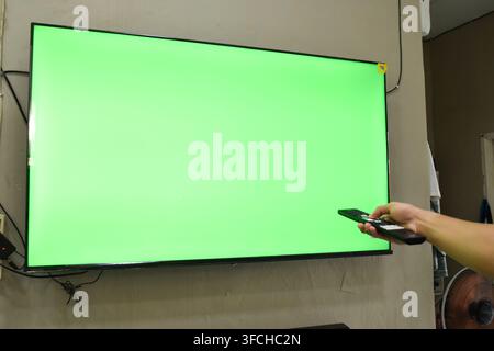 Concetto di schermo verde. Mano giovane uomo sul divano e guardare la tv Foto Stock