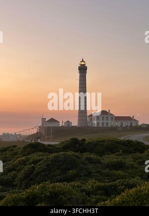 Il faro Farol de Leça, situato sulla costa atlantica a Matosinhos, Porto, Portogallo, è catturato al tramonto. Il faro si erge alto con il suo dis Foto Stock