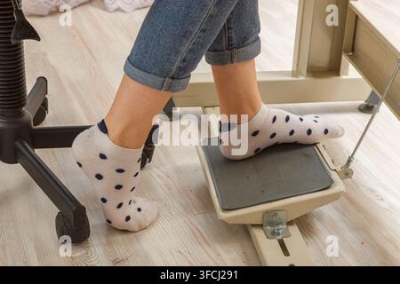 Piedi femmina sul pedale di una macchina da cucire, primo piano del motore Foto Stock