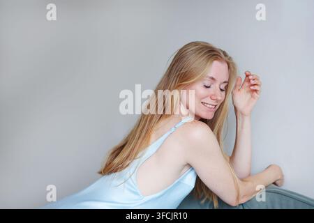 Giovane donna felice con lentiggini che sorride con gli occhi chiusi, stile di vita rilassato e concetto di bellezza naturale. Foto Stock