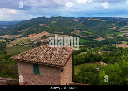Vista panoramica della campagna umbra da Montone, Italia. Casa in mattoni con tetto in terracotta che si affaccia su colline verdi e campi a Perugia Foto Stock