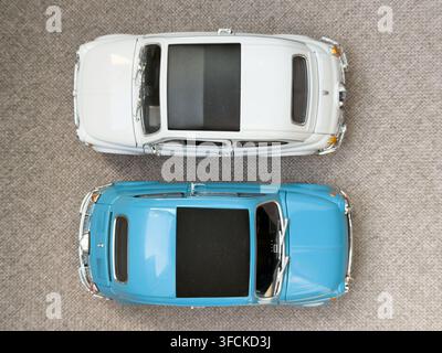 Vista dall'alto di due modelli di auto classiche Fiat 500 in metallo pressofuso blu e bianchi su una superficie di tessuto, fotografati in studio Foto Stock