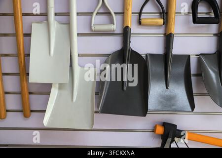 Immagine ad alta risoluzione in primo piano che mostra una varietà di pale e vanghe da giardino di diverse dimensioni e colori, tra cui bianco dipinto e nero opaco Foto Stock
