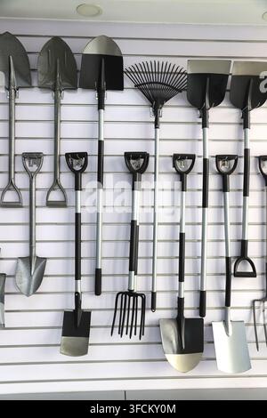 Immagine in primo piano ad alta risoluzione che cattura una varietà di attrezzi da giardino tra cui pale, zappe, forche e rastrelli da giardino disposti ordinatamente su uno sfondo bianco Foto Stock