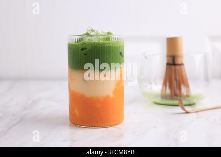 Prima piano di latte freddo al mango e matcha su tavolo bianco Foto Stock