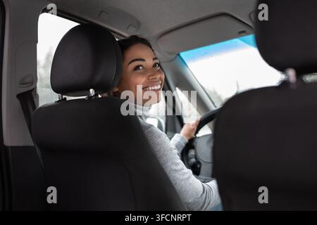 Giovane donna che guida l'auto, viaggio di donna d'affari in tempo soleggiato Foto Stock