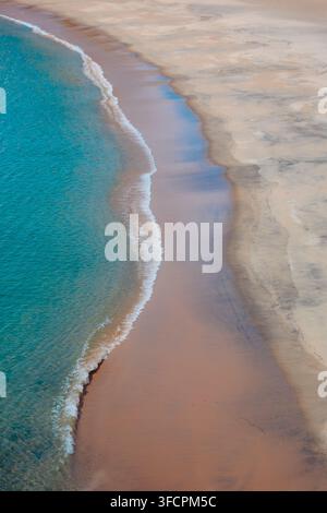 Morbide onde turchesi che incontrano una riva sabbiosa Foto Stock