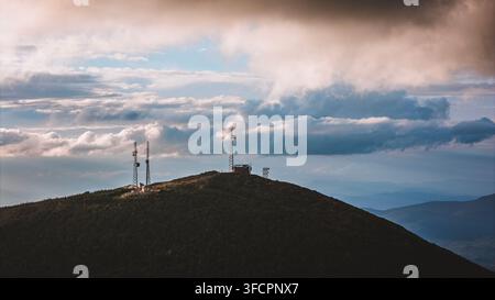 Torri di comunicazione distanti sulla cima di una montagna boscosa Foto Stock