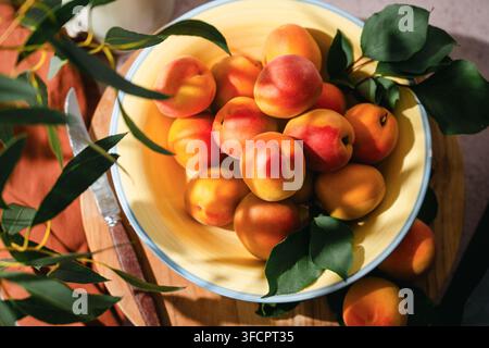 Frutti di albicocca freschi e maturi in una ciotola gialla, cibo estivo Foto Stock