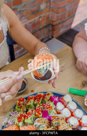 Donna che intinge un rotolo di sushi al salmone nella salsa di soia Foto Stock