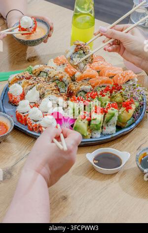 Amici che si godono insieme un grande vassoio di sushi misto Foto Stock