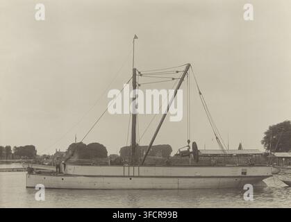 Vos, fotografia, Grua galleggiante Vos. Foto incollata su cartone con informazioni tecniche sulla nave in tedesco, francese, spagnolo e inglese. Parte della cartella contenente 44 foto di draghe della ditta A. Bos & JP Heijblom a Dordrecht., nome: 'HJ Tollens C. Hzn. Dordrecht', fotografo: Henricus Jacobus Tollens, Dordrecht, c. 1900 - c. 1910, carta, cartone, stampa al gelatino d'argento, stampa al gelatino d'argento sviluppata incollata su cartone, altezza 165 mm x larghezza 225 mm, a vapore), draga, macchina da dragaggio., Una grande barca è mostrata galleggiante su acque calme con un alto albero centrale e un ang Foto Stock