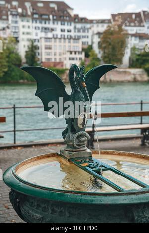 Fontana tradizionale del Basalisco con stemma sulla passeggiata lungofiume del Reno a Basilea, Svizzera Foto Stock