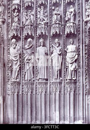 Un'intaglio in pietra dettagliata sul portale centrale della cattedrale di Strasburgo, che presenta più figure in abiti in stile gotico, con dettagli architettonici intricati che le circondano, in una fotografia del landmark di Strasburgo. Foto Stock